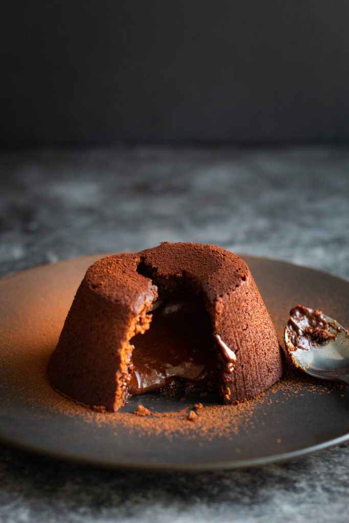 Mini Chocolate Lava Cake dusted with cocoa and cut open to reveal gooey centre