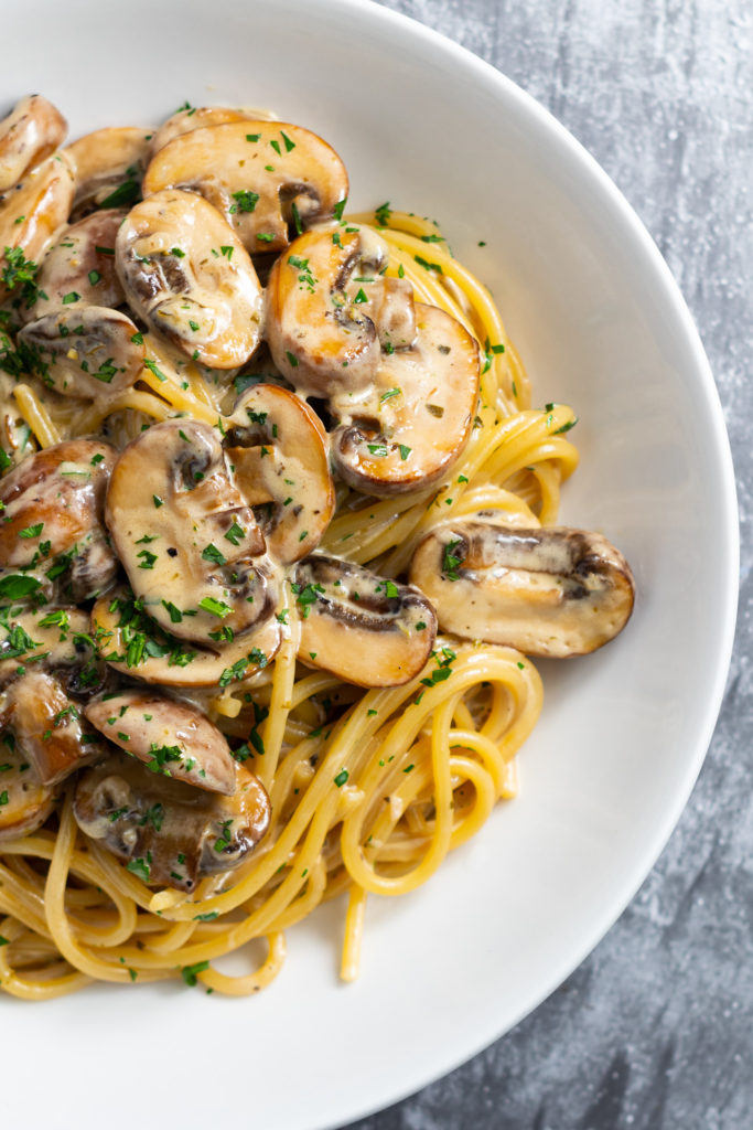 Close up of creamy mushroom pasta in a bowl, viewed from above