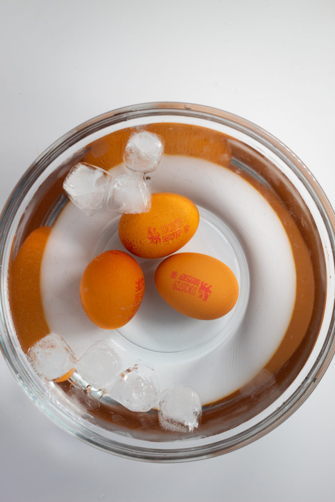 3 boiled eggs cooling in ice bath