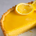 Lemon tart with slice removed showing smooth creamy filling