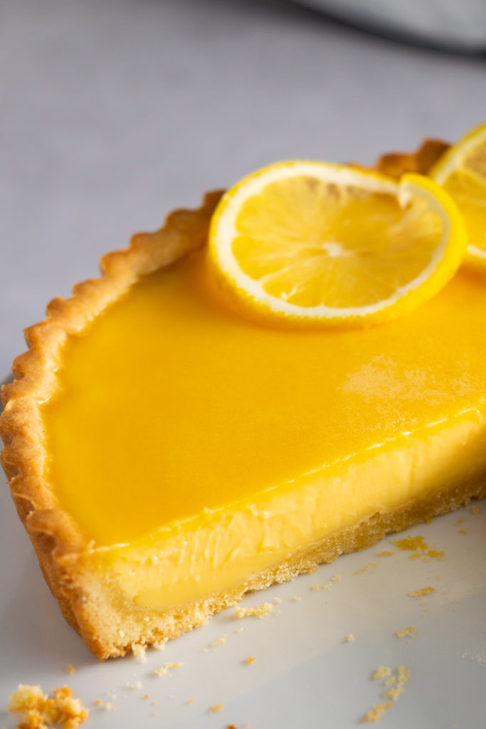 Lemon tart with slice removed showing smooth creamy filling