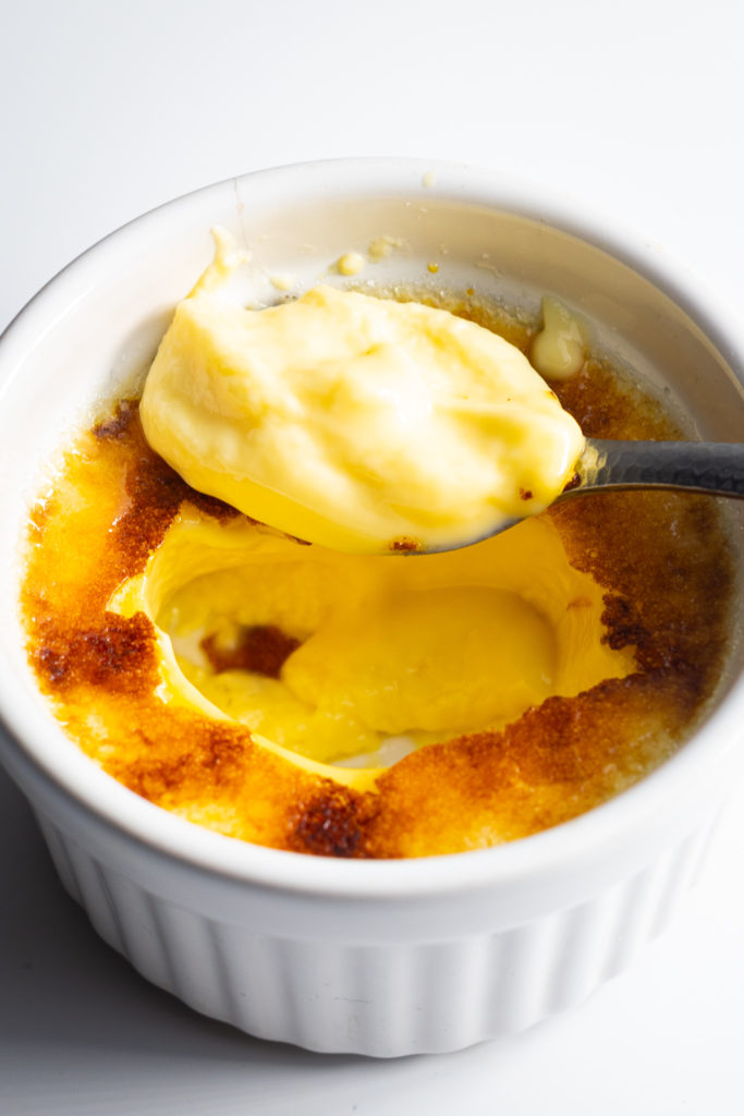 Crème Brulée with a spoonful of custard on a spoon from the centre 