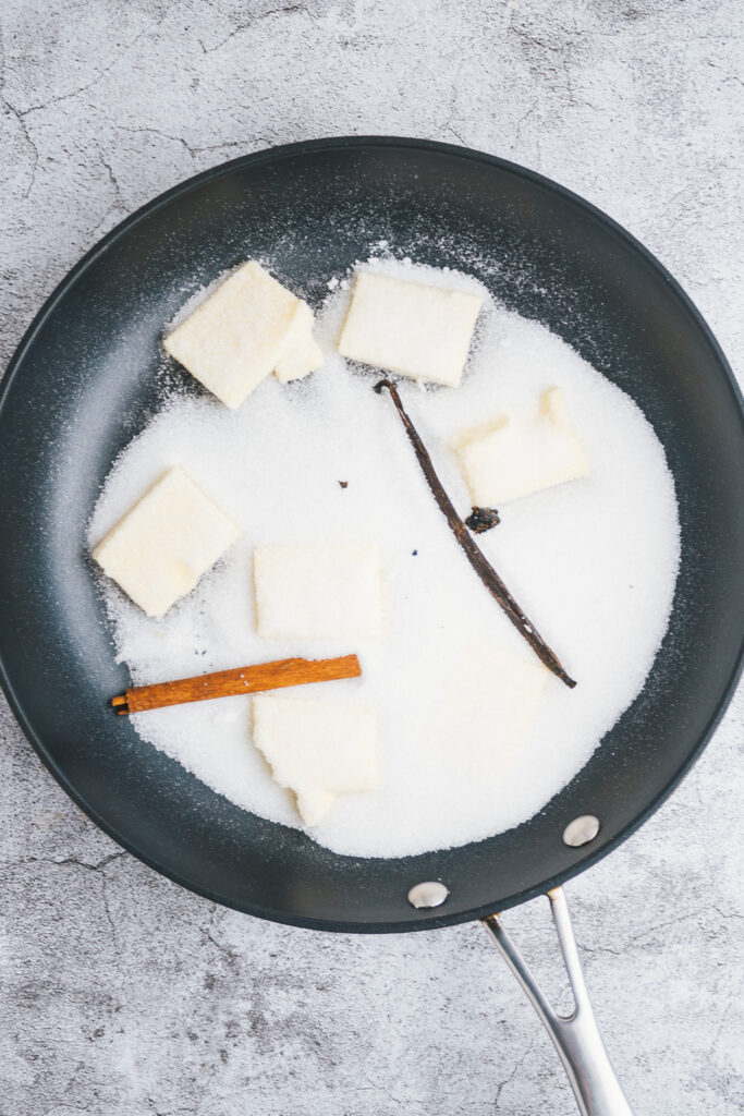 Sugar and butter in a frying pan with vanilla pod and cinnamon stick