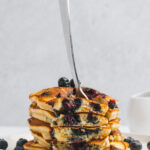 Stack of Blueberry Pancakes with forkful showing inner pancake