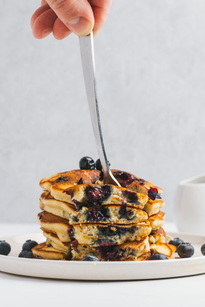 Stack of Blueberry Pancakes with forkful showing inner pancake