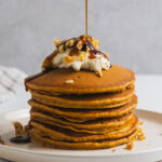 Maple syrup poured onto a stack of carrot cake pancakes