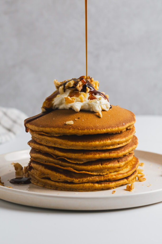 Maple syrup poured onto a stack of carrot cake pancakes