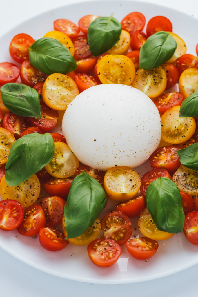 Burrata Caprese Salad on a plate with basil leaves