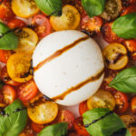 caprese salad showing burrata surrounded by halved cherry tomatoes
