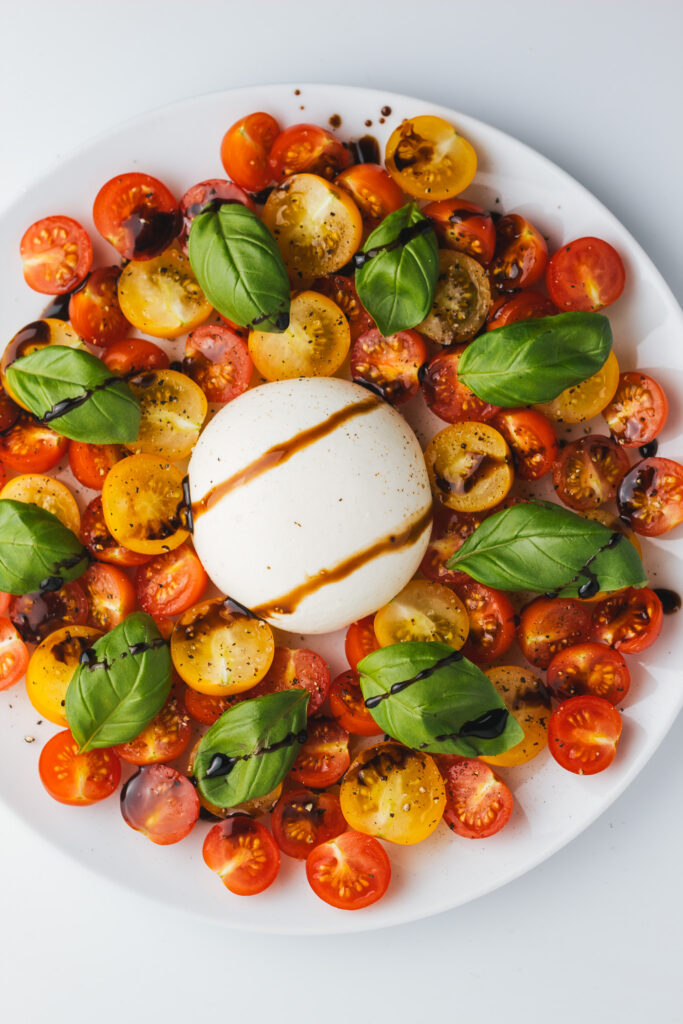 Burrata Caprese Salad on a plate drizzled with balsamic reduction
