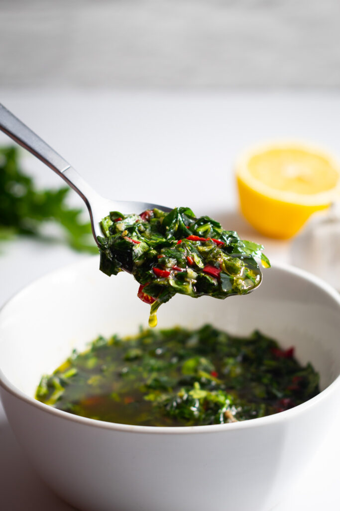 Chimichurri verde on a spoon above bowl
