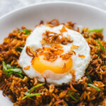 Spicy fried rice in a bowl topped with a crispy fried egg and crispy fried shallots