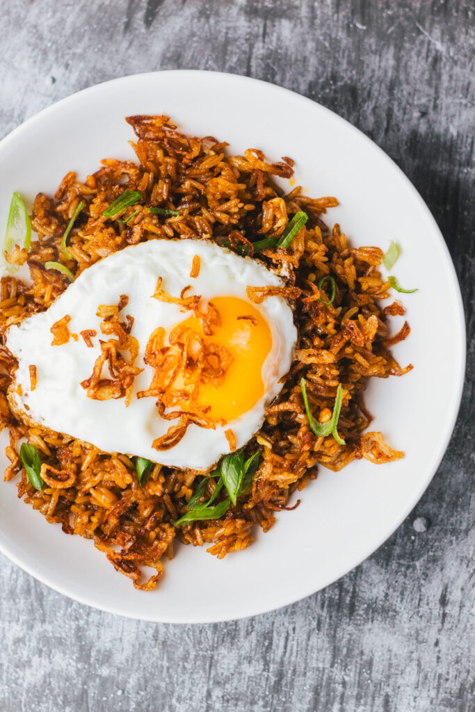 Nasi goreng kampung in a bowl topped with a crispy fried egg and crispy fried shallots