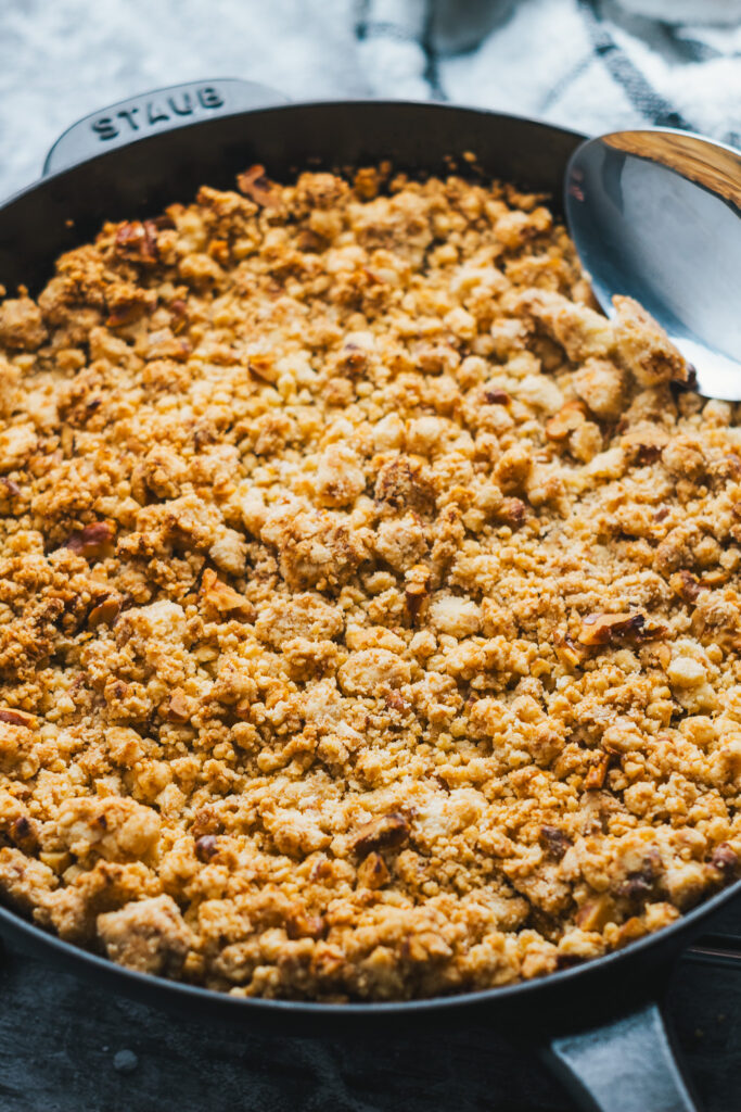 Apple crisp in cast iron pan with serving spoon