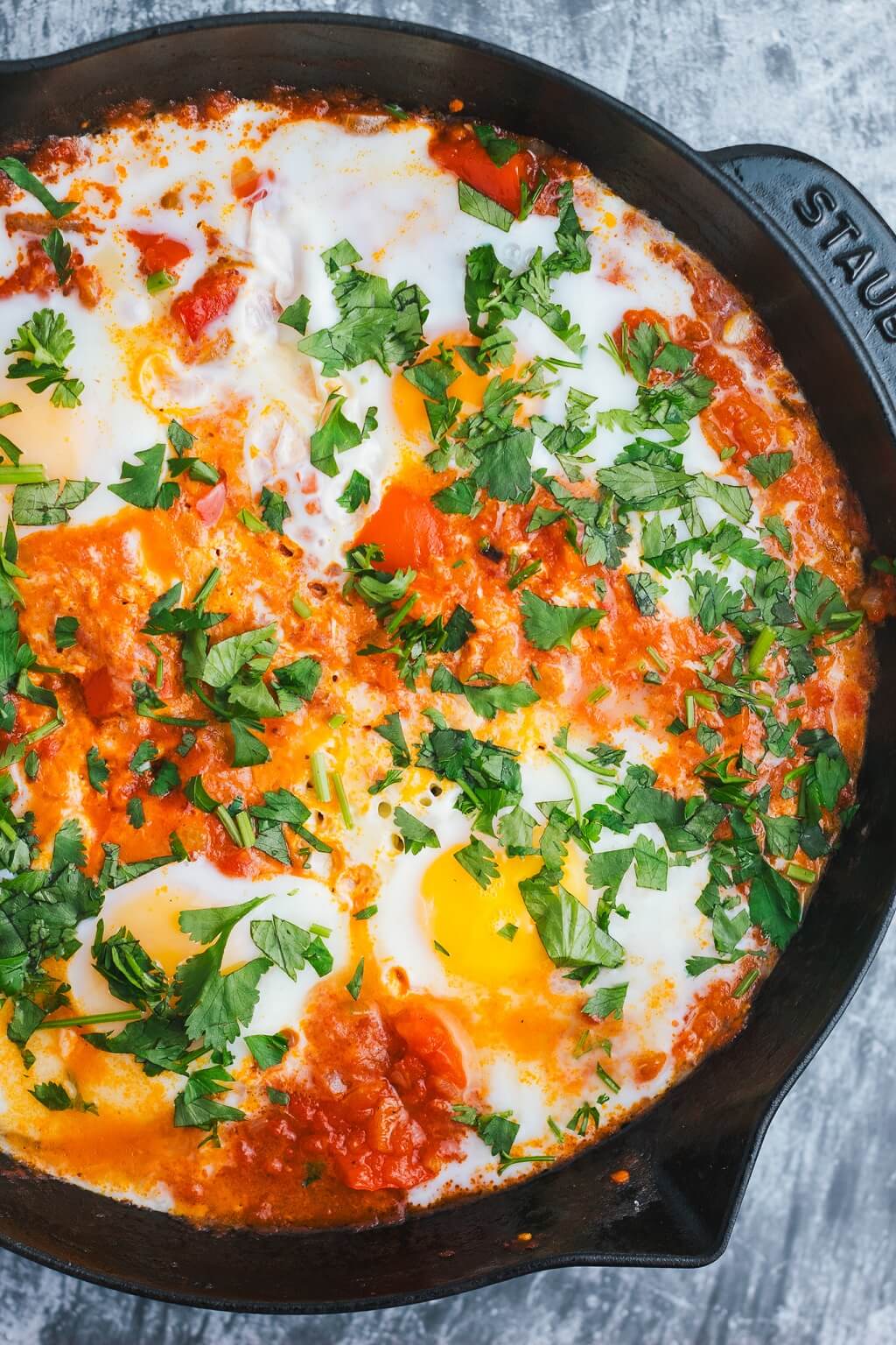 Shakshuka topped with chopped herbs in a frying pan 