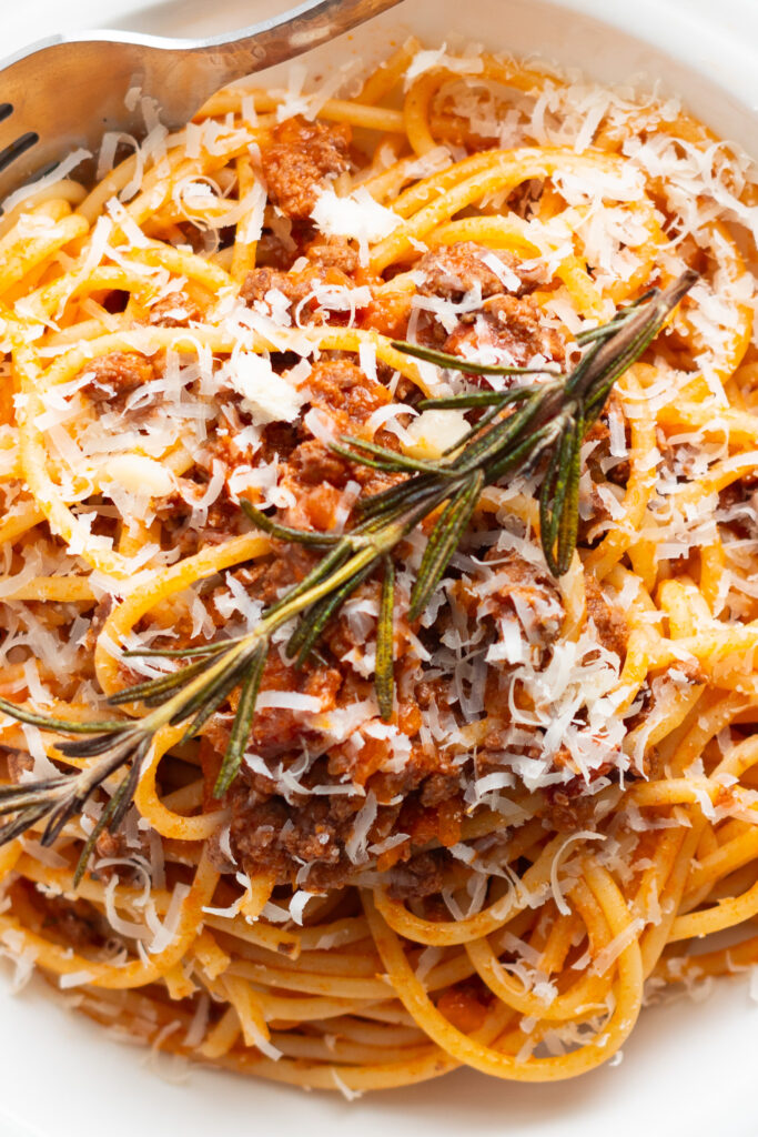 Spaghetti bolognese topped with fried rosemary