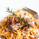 Spaghetti bolognese topped with fried rosemary