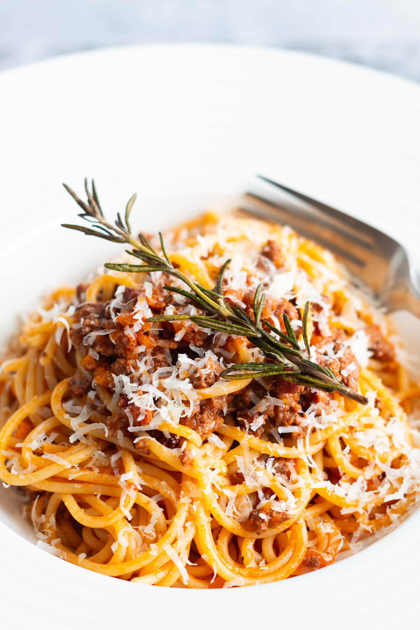 Spaghetti Bolognese topped with fried rosemary