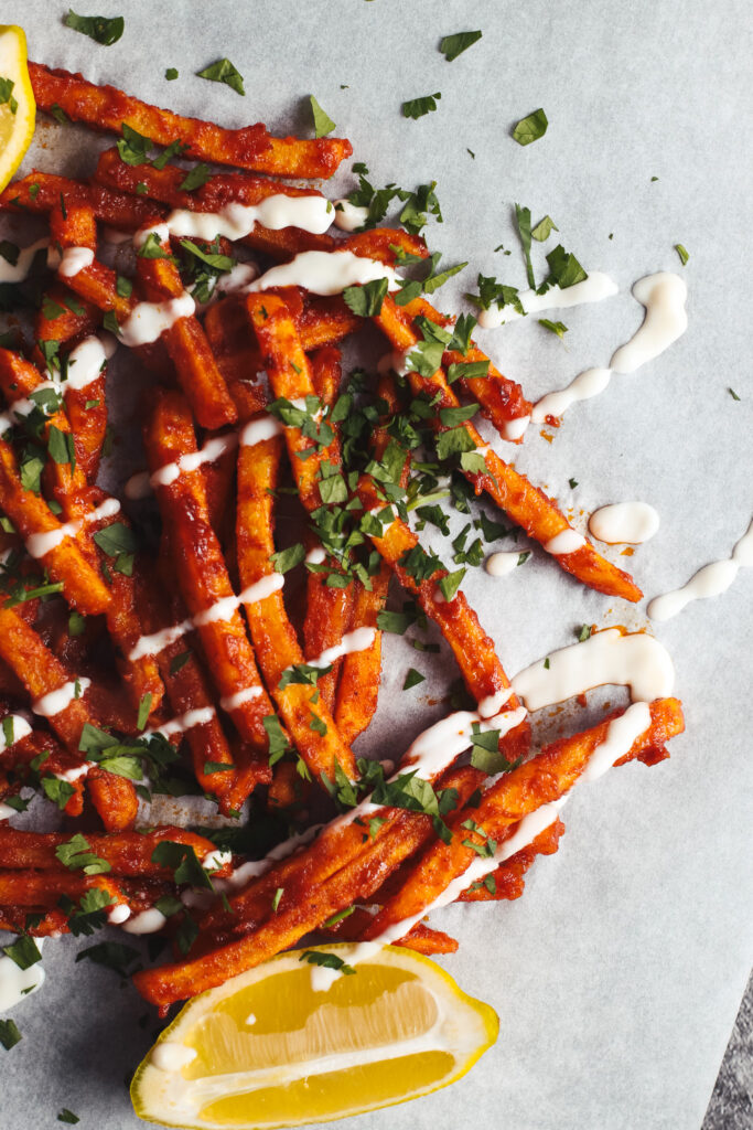 Masala fries on a plate topped with yoghurt and coriander