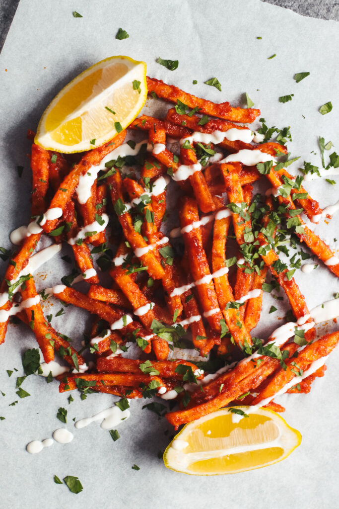 Masala fries on a plate topped with yoghurt and coriander