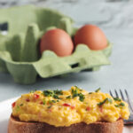 Scrambled eggs on toast with a carton of eggs