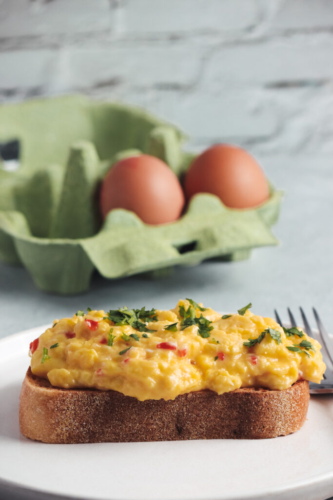 Scrambled eggs on toast with a carton of eggs