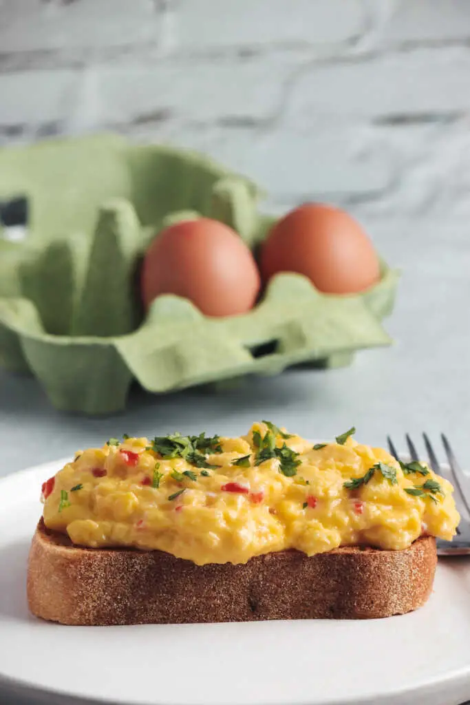 Chilli scrambled eggs on golden toast with a carton of eggs in the background.