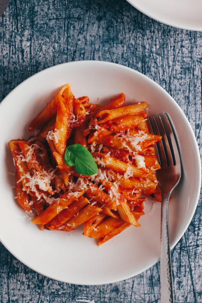 Bowl of Penne Napoli topped with parmesan and basil
