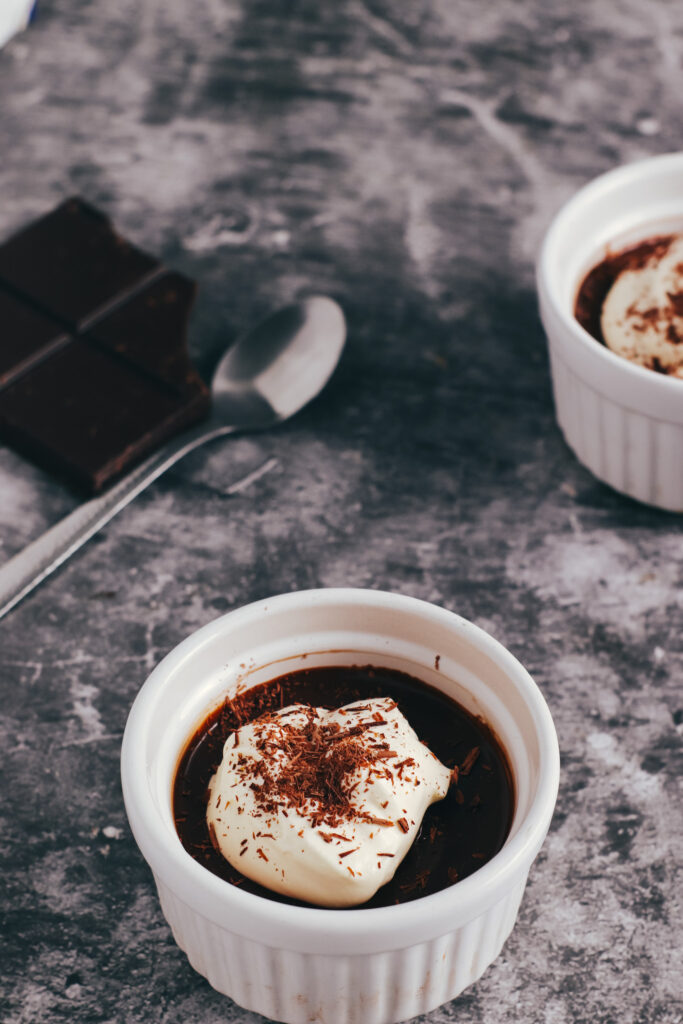 Chocolate pots de creme with a spoon and some chocolate