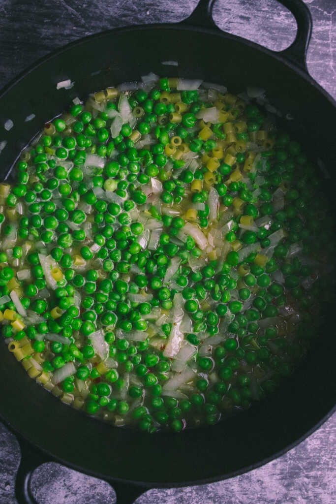 Simmering peas, pasta and onions in water