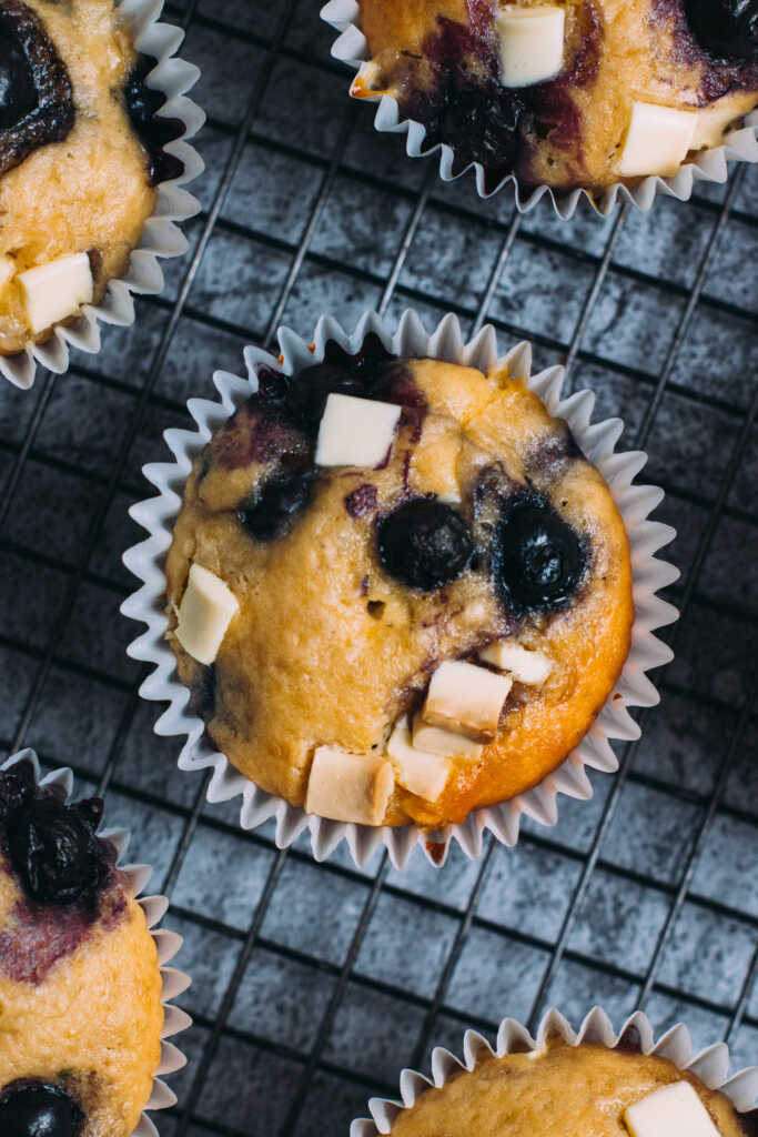 Close up of a white chocolate and blueberry muffin on a cooling rack