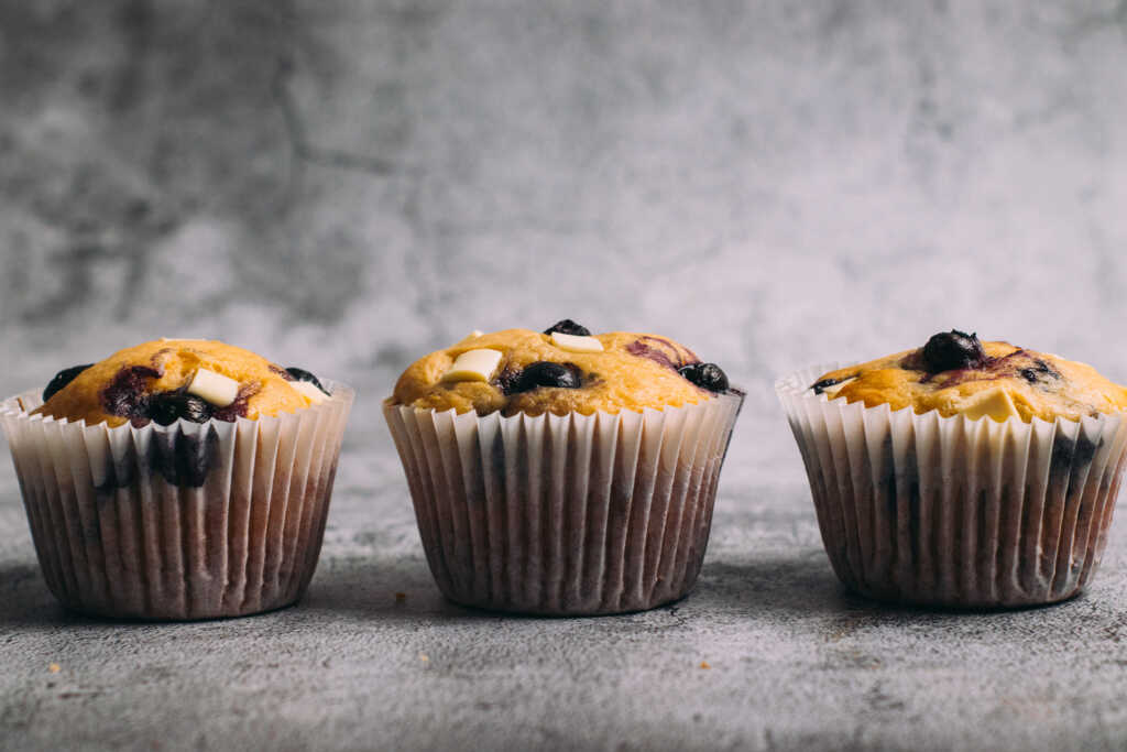 Three white chocolate and blueberry muffins in a row