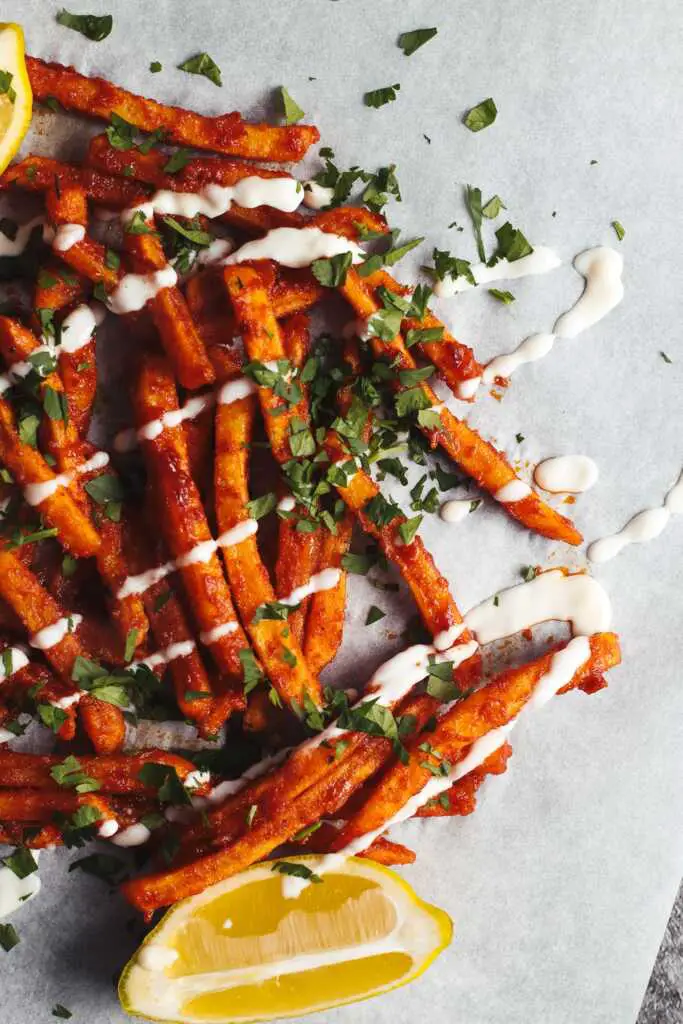 Crispy masala fries coated in spicy tomato masala sauce with coriander garnish