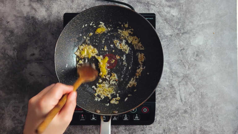 Garlic ginger paste and onions in a frying pan