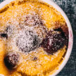 Close up of easy mini clafoutis in a ramekin dusted with icing sugar