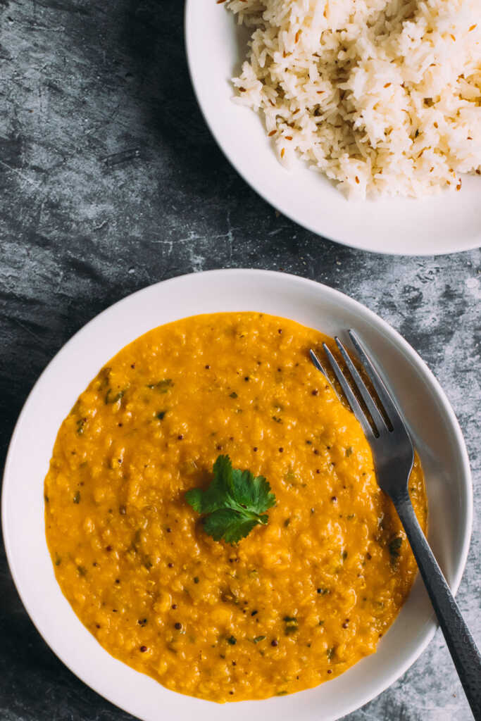 Bengali masoor dal in a bowl alongside a bowl of rice