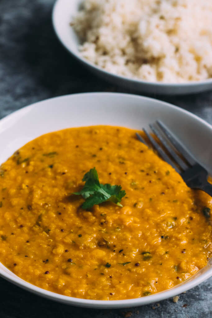 Bengali masoor dal in a bowl with a bowl of rice