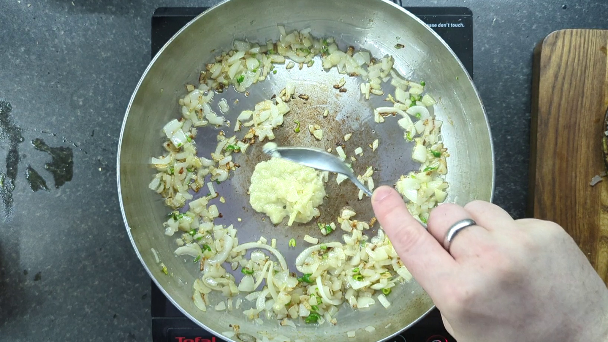 adding garlic ginger paste to onions in a frying pan