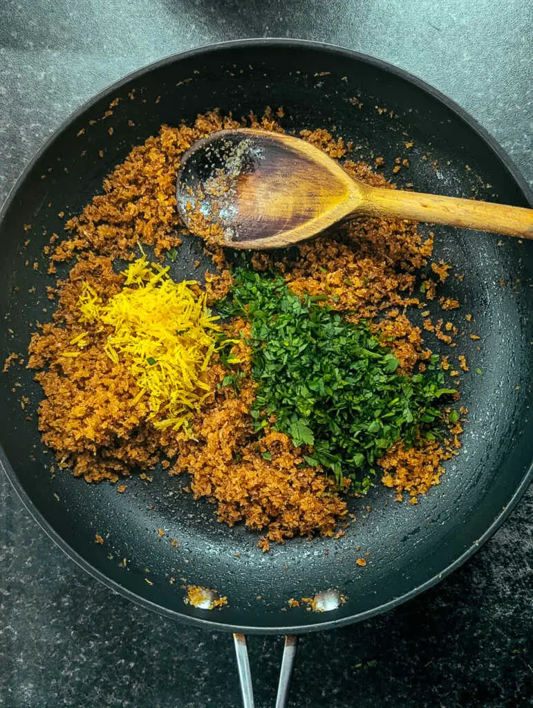 Pangrattato breadcrumbs with grated lemon and chopped parsley in a pan
