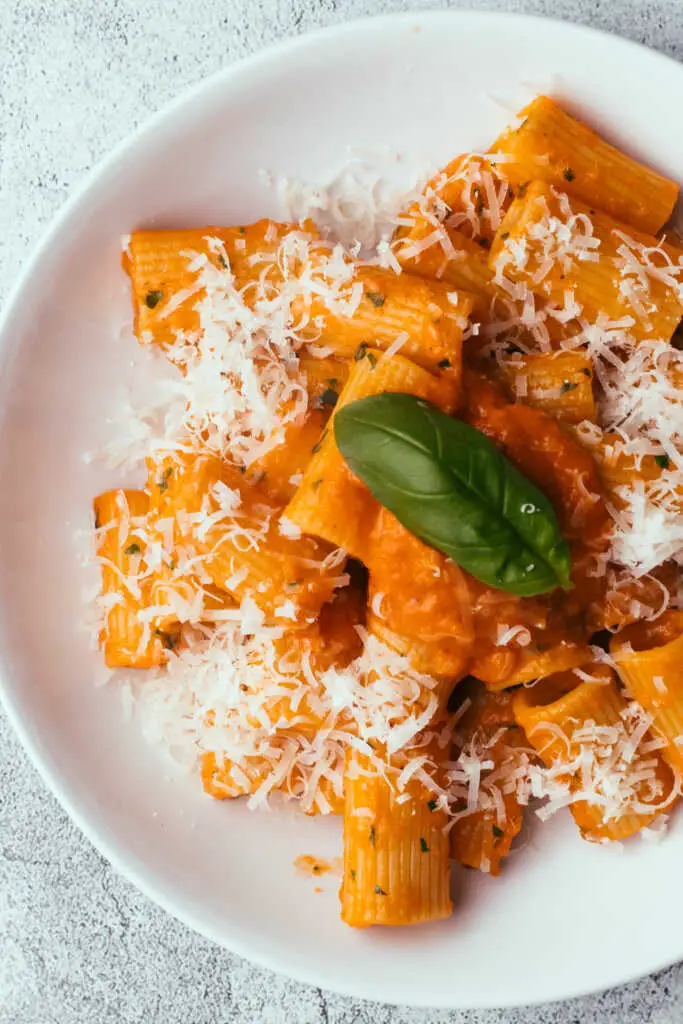 Tomato butter pasta in a bowl topped with grated parmesan
