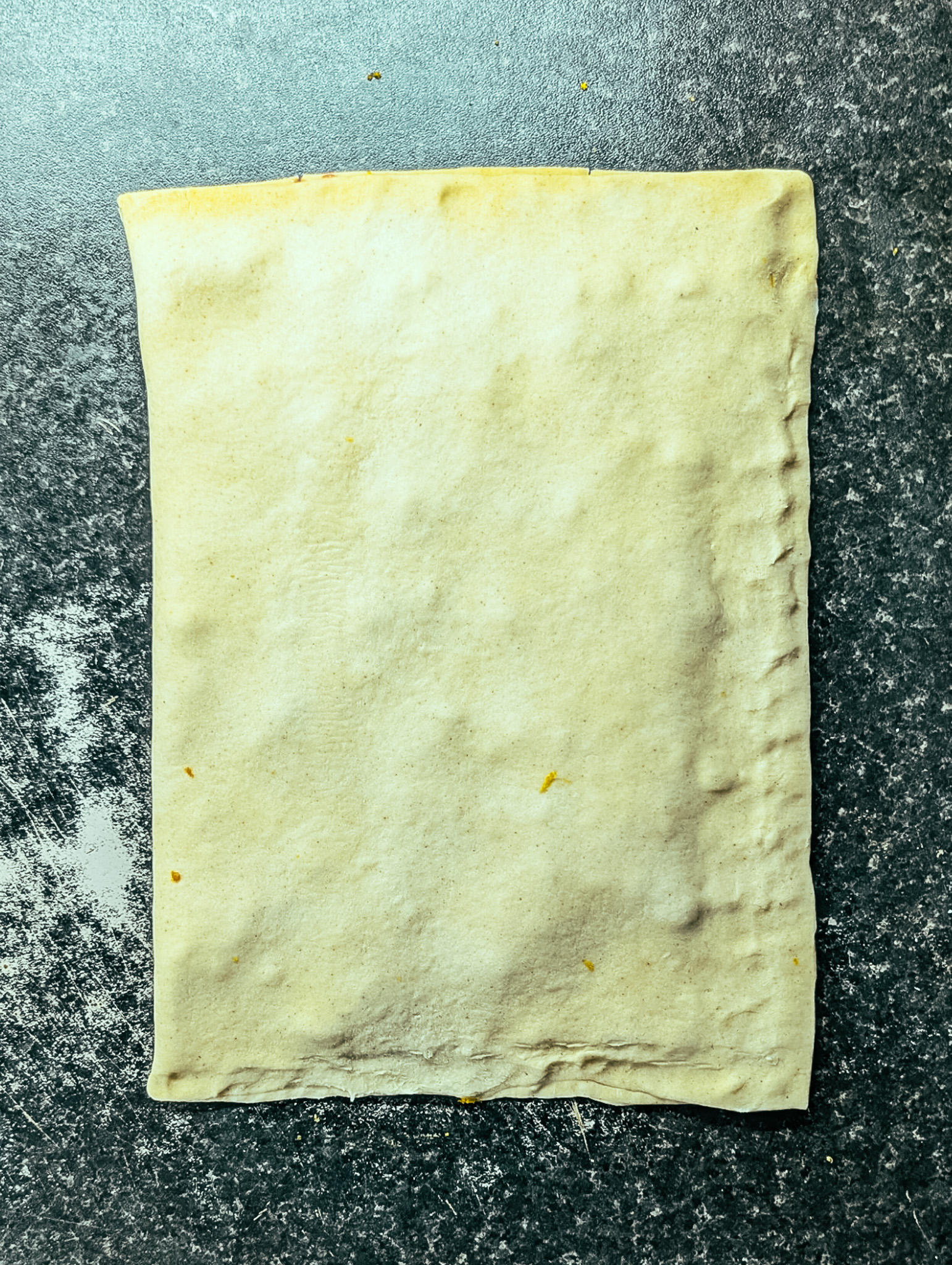 Puff pastry folded over raspberry jam and white chocolate chips, ready to slice for chocolate twists.