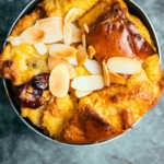 Overhead shot of brioche bread and butter pudding in a baking dish with almond topping