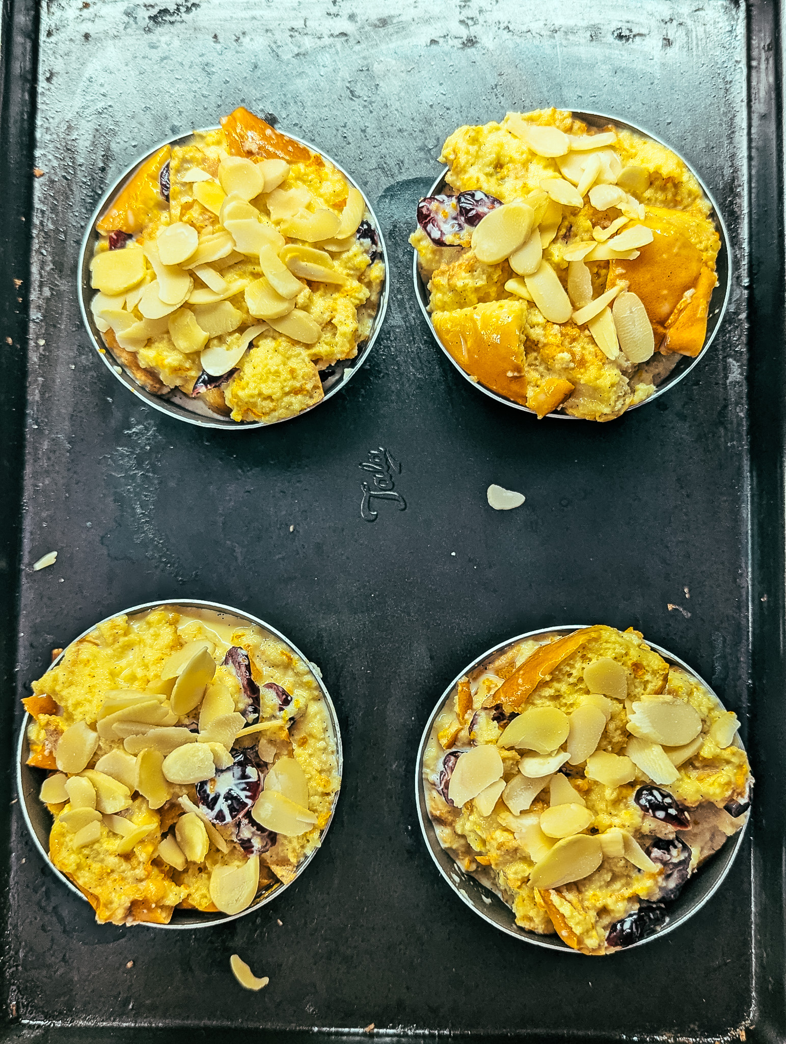 Individual brioche bread and butter puddings topped with almonds before baking