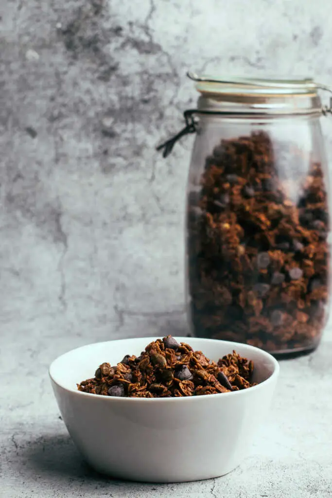 Bowl of mocha nut free granola with a jar of granola in the background.
