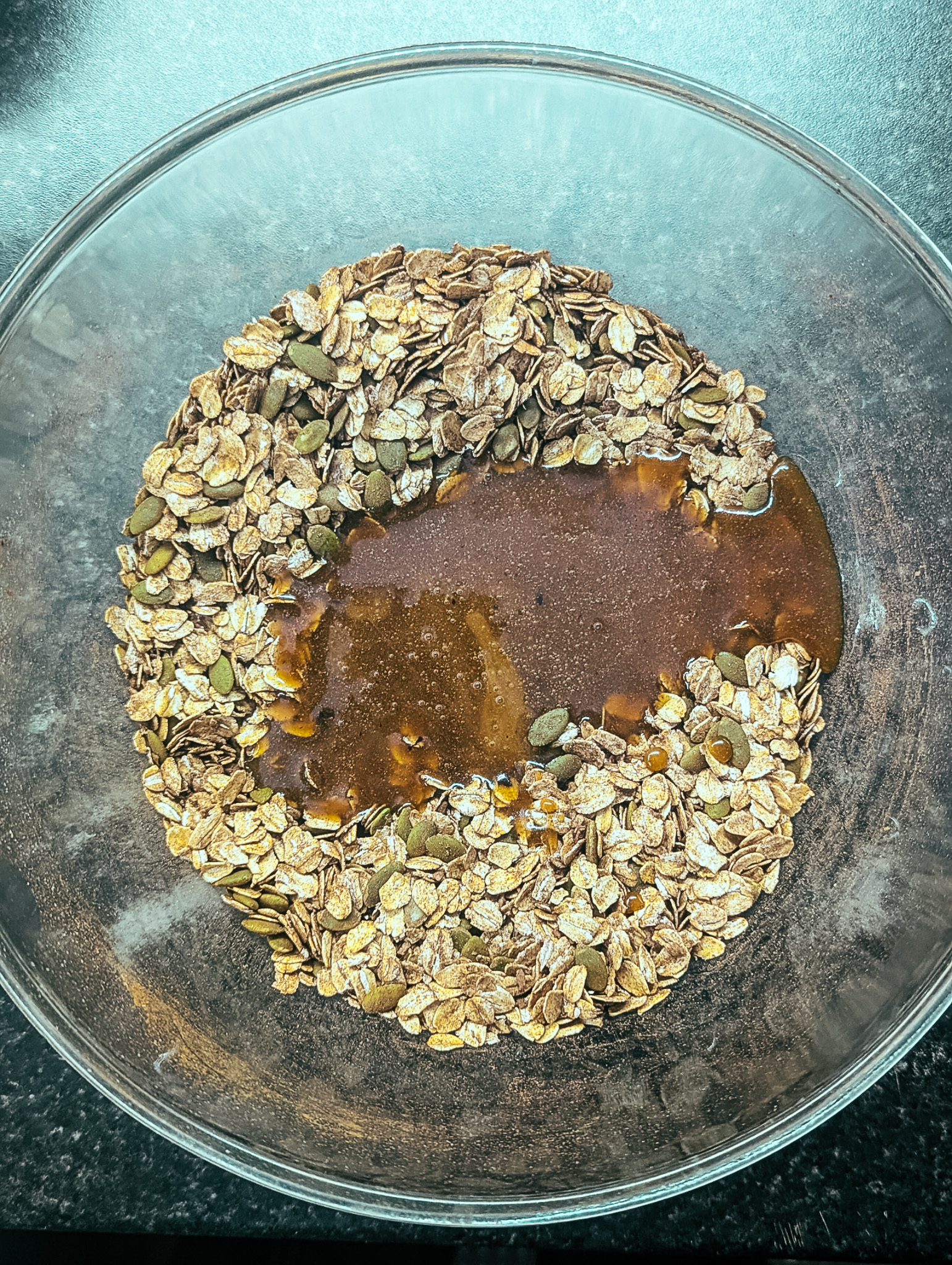 Syrup poured over oats and seeds for mocha nut free granola.