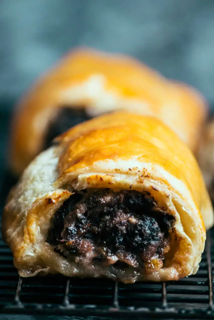 Close-up of golden black pudding sausage roll with flaky pastry