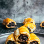 Stack of black pudding sausage rolls on grey plate