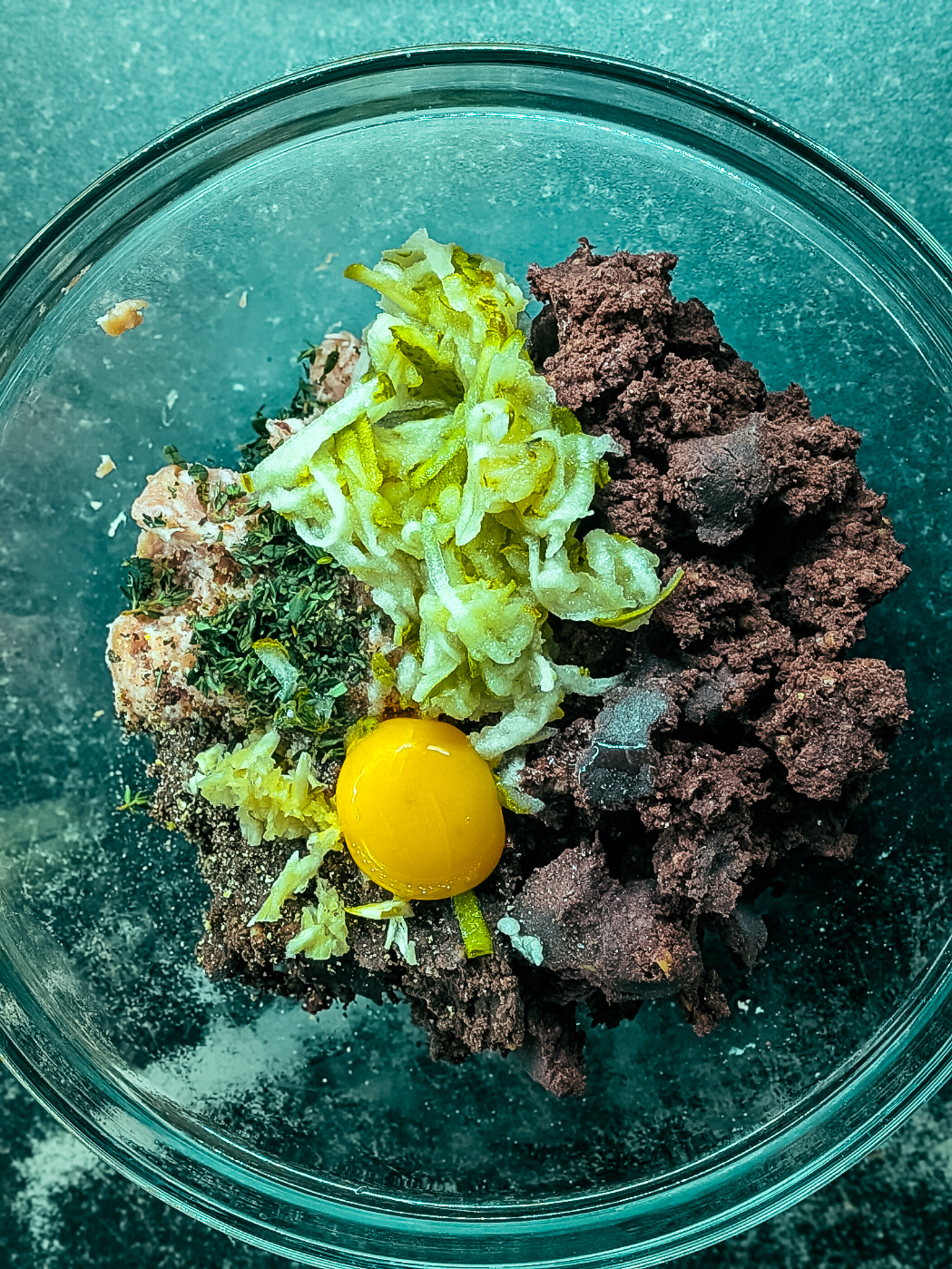 Mixing black pudding, sausage meat, grated apple and herbs in a bowl