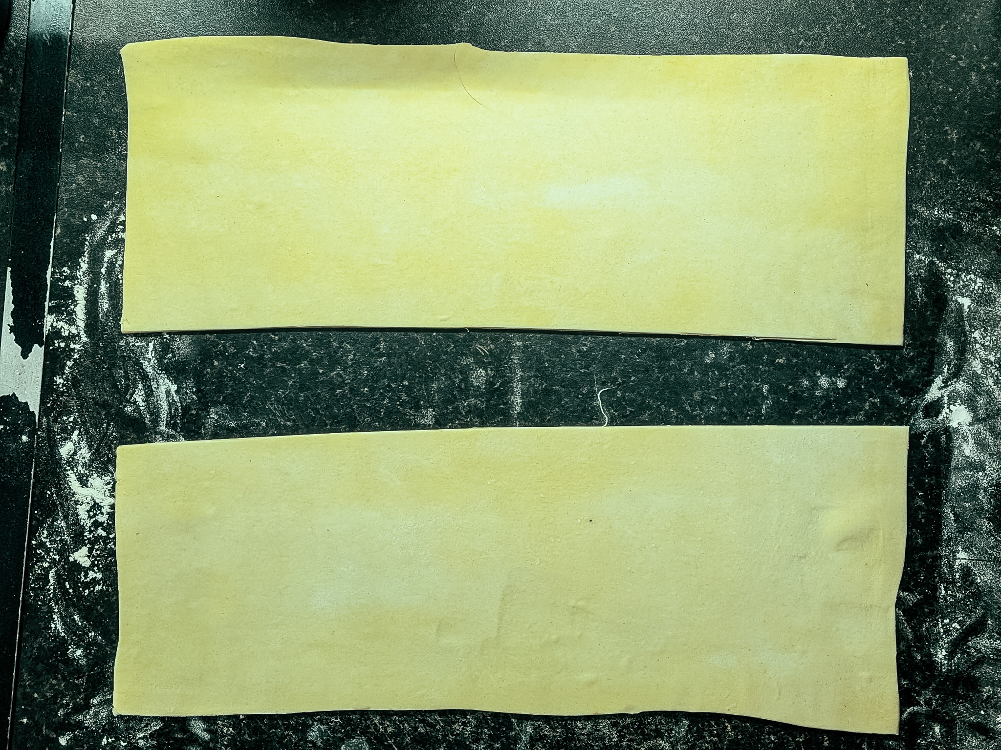 Strips of puff pastry cut and prepared for rolling sausage filling