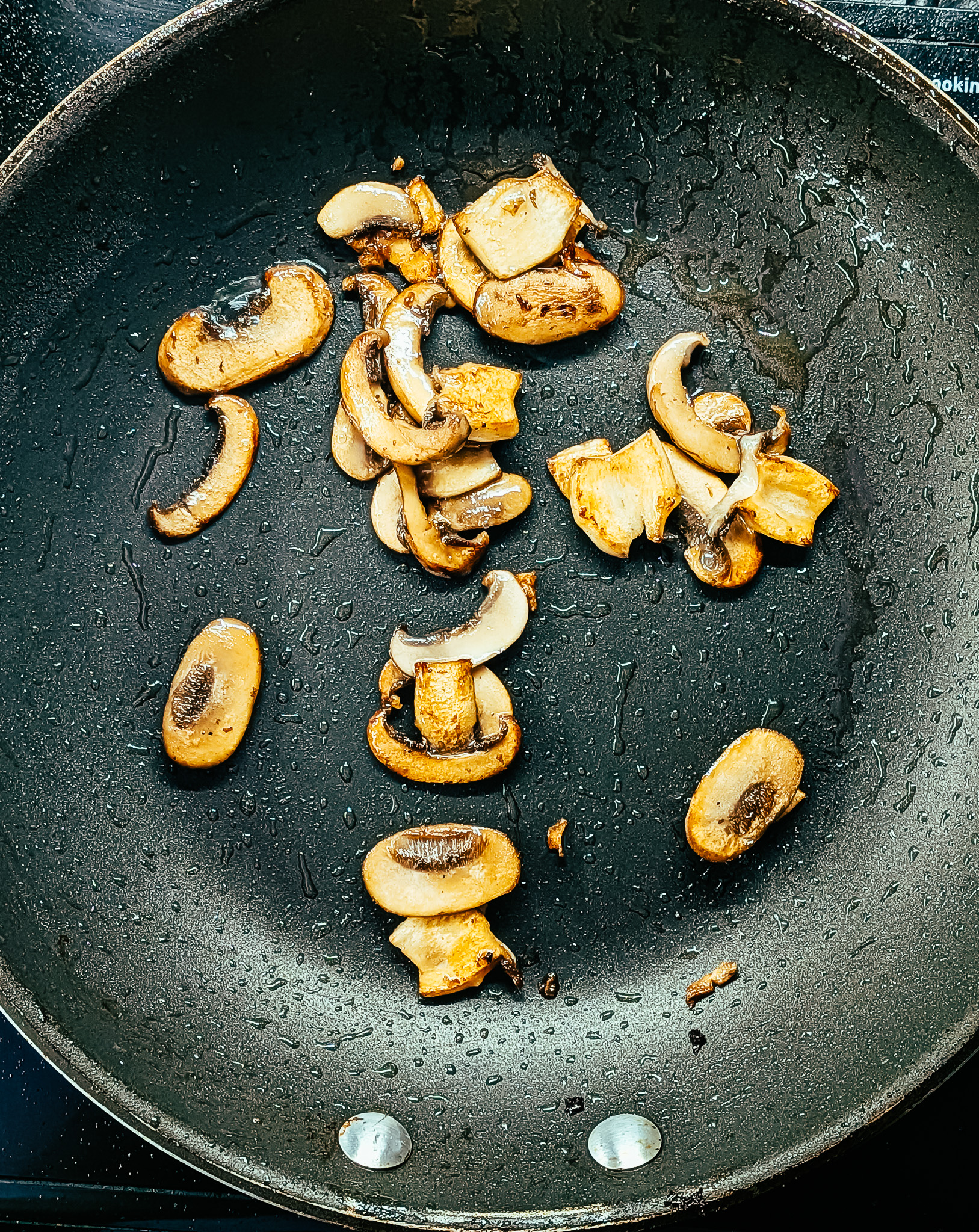 Sliced mushrooms frying in a pan for a rustic country omelette